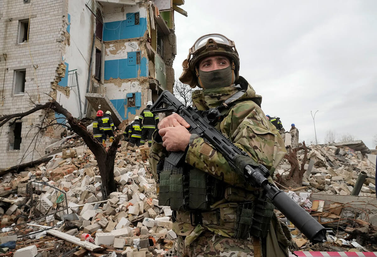 Ukrajinski vojnik pored zgrade srušene u bombardovanju