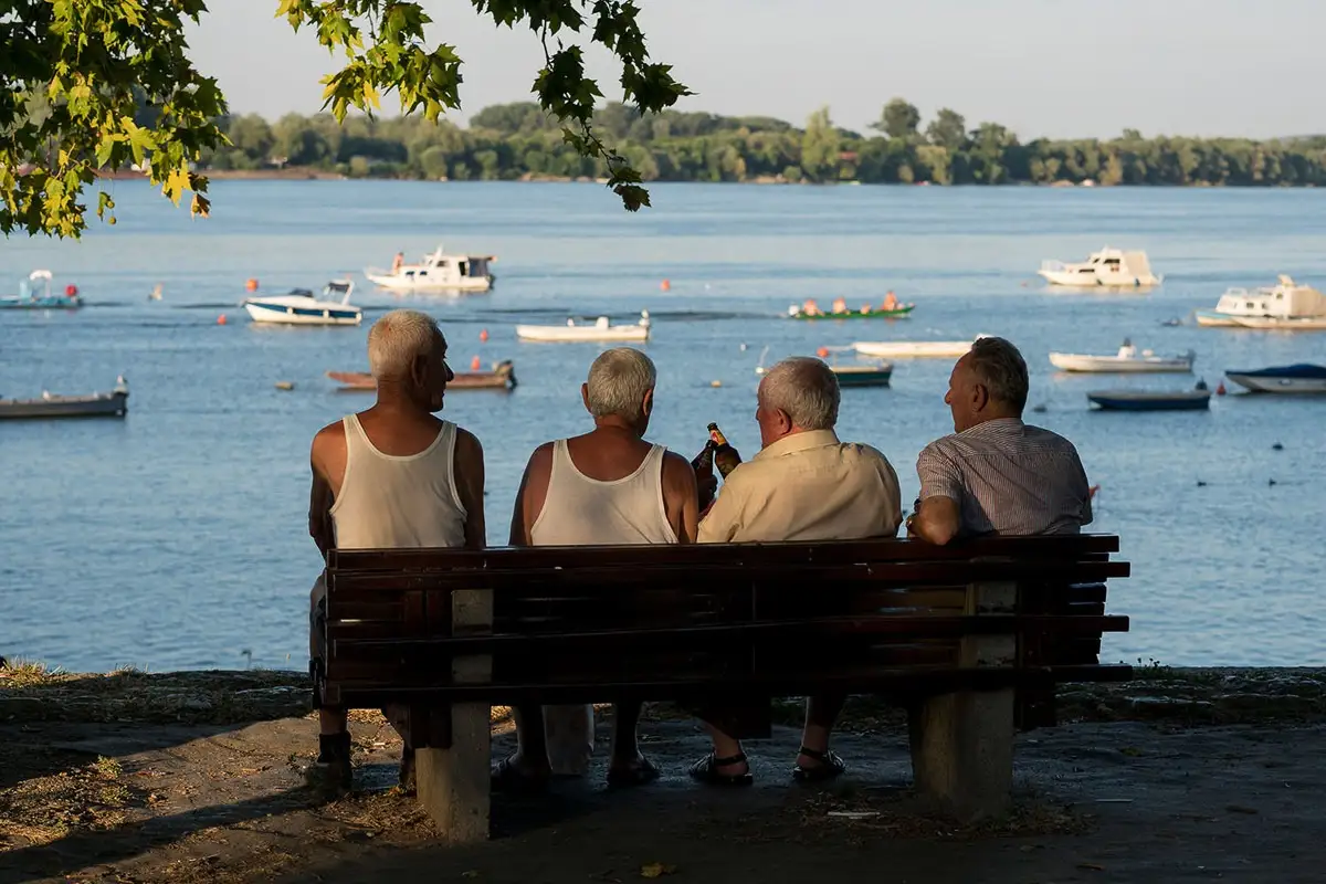 penzioneri sede na klupi na keju pored dunava